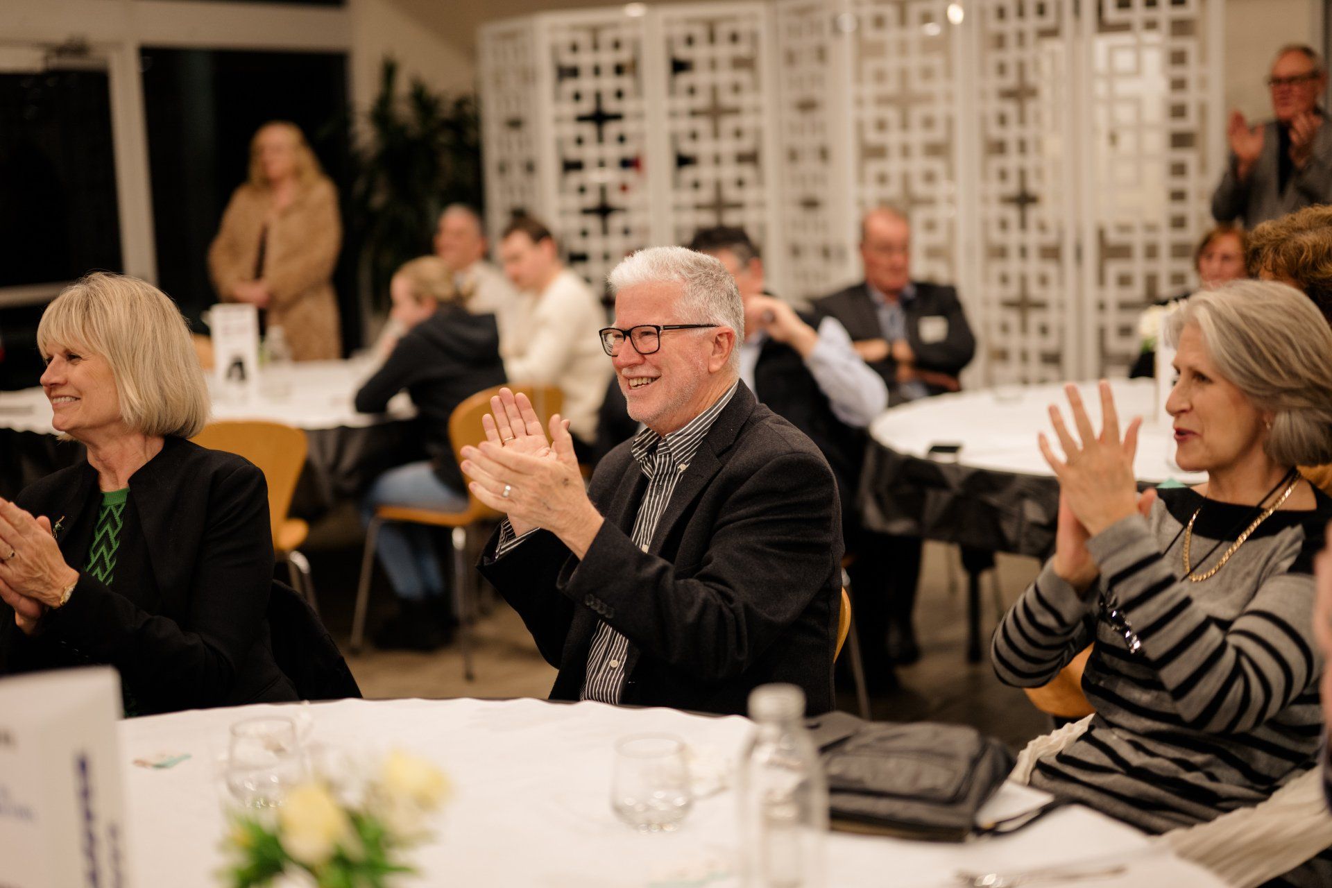 A group of people are sitting at a table clapping their hands.