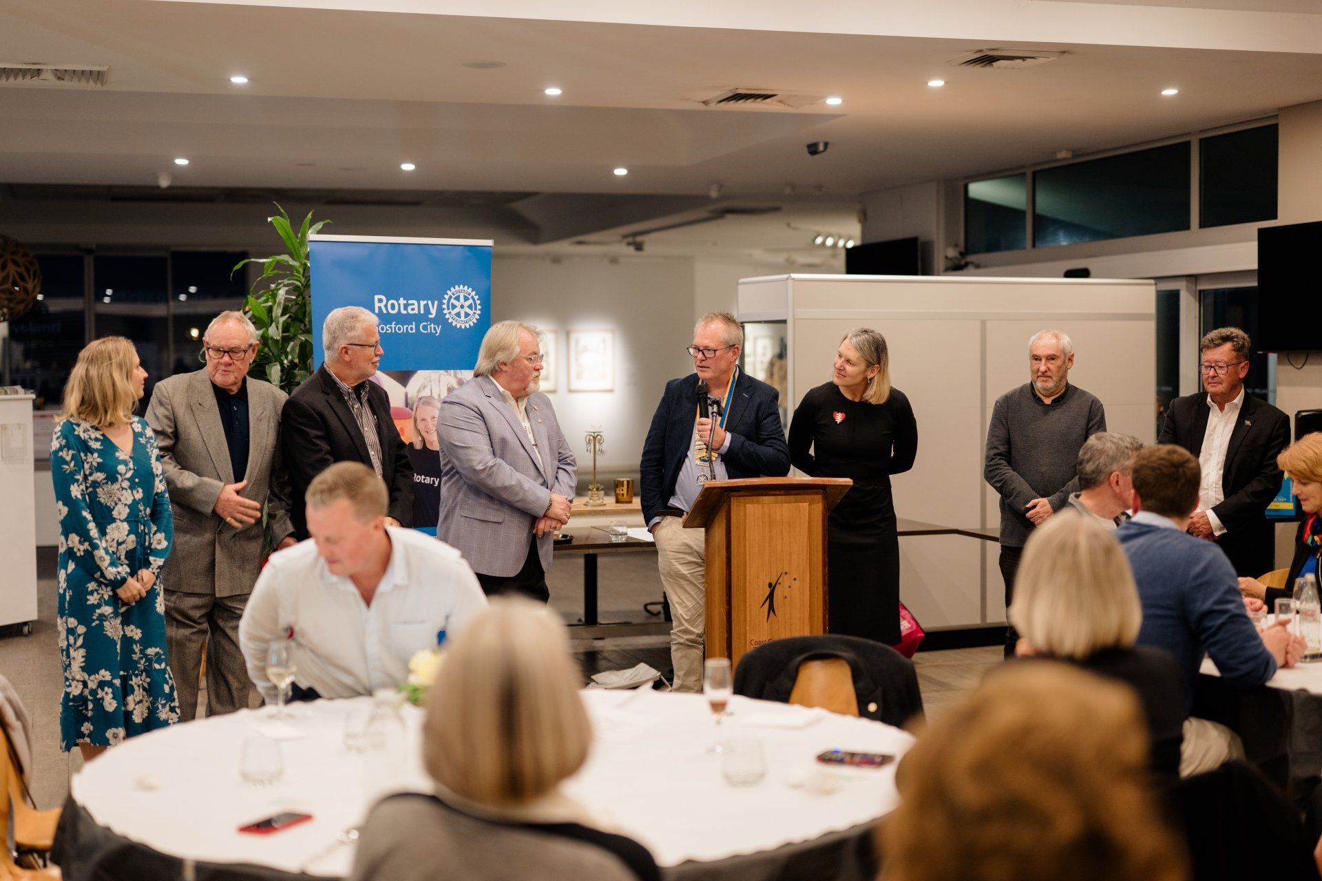 A group of people are standing around a podium in a room.
