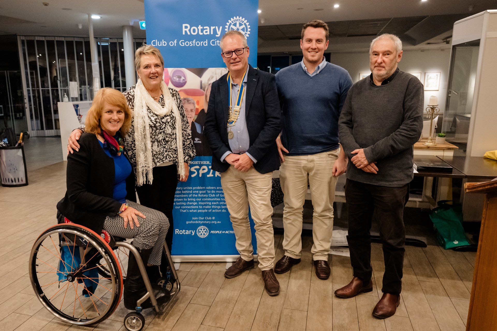 A woman in a wheelchair is standing next to a group of people.