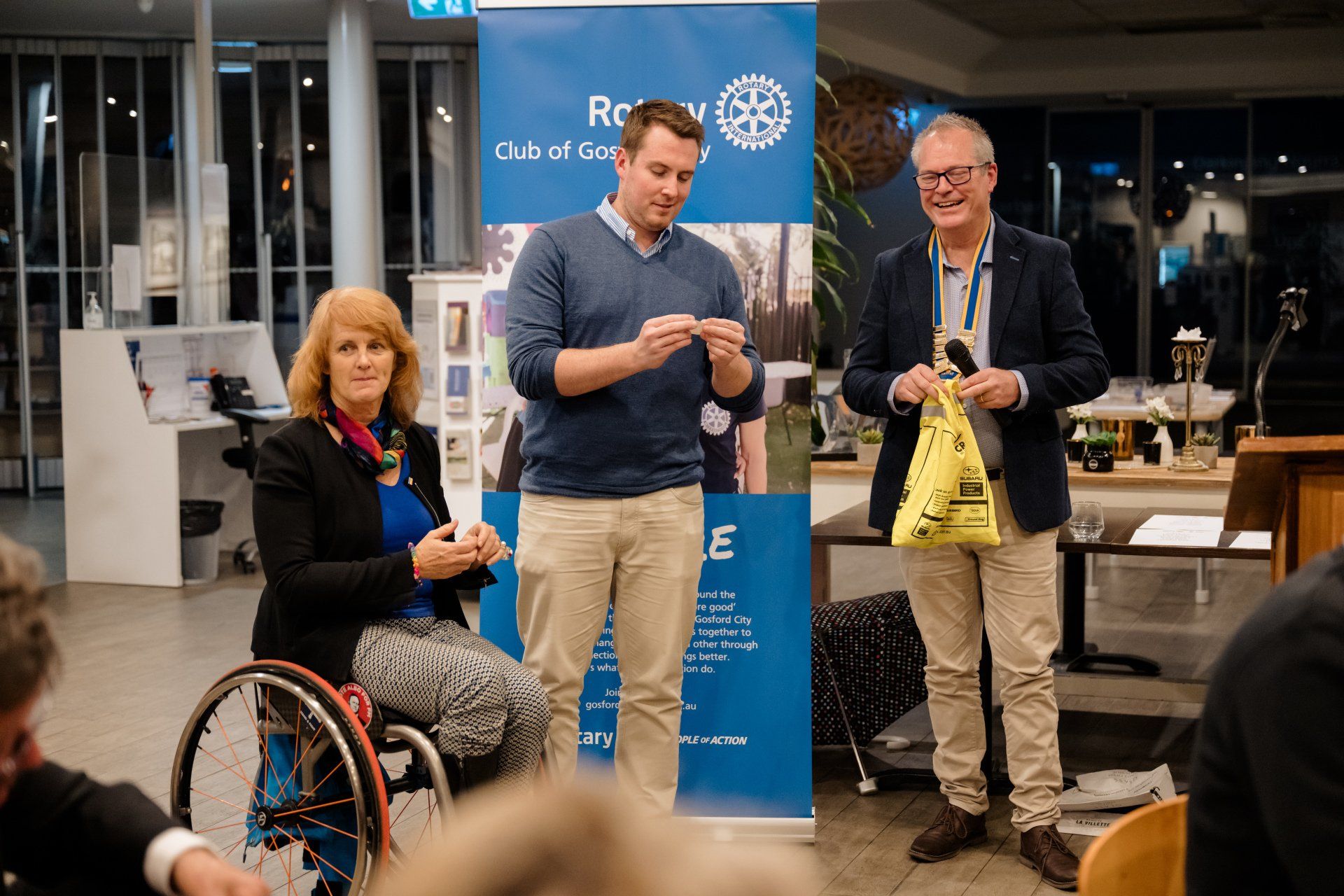 A woman in a wheelchair is standing next to two men.