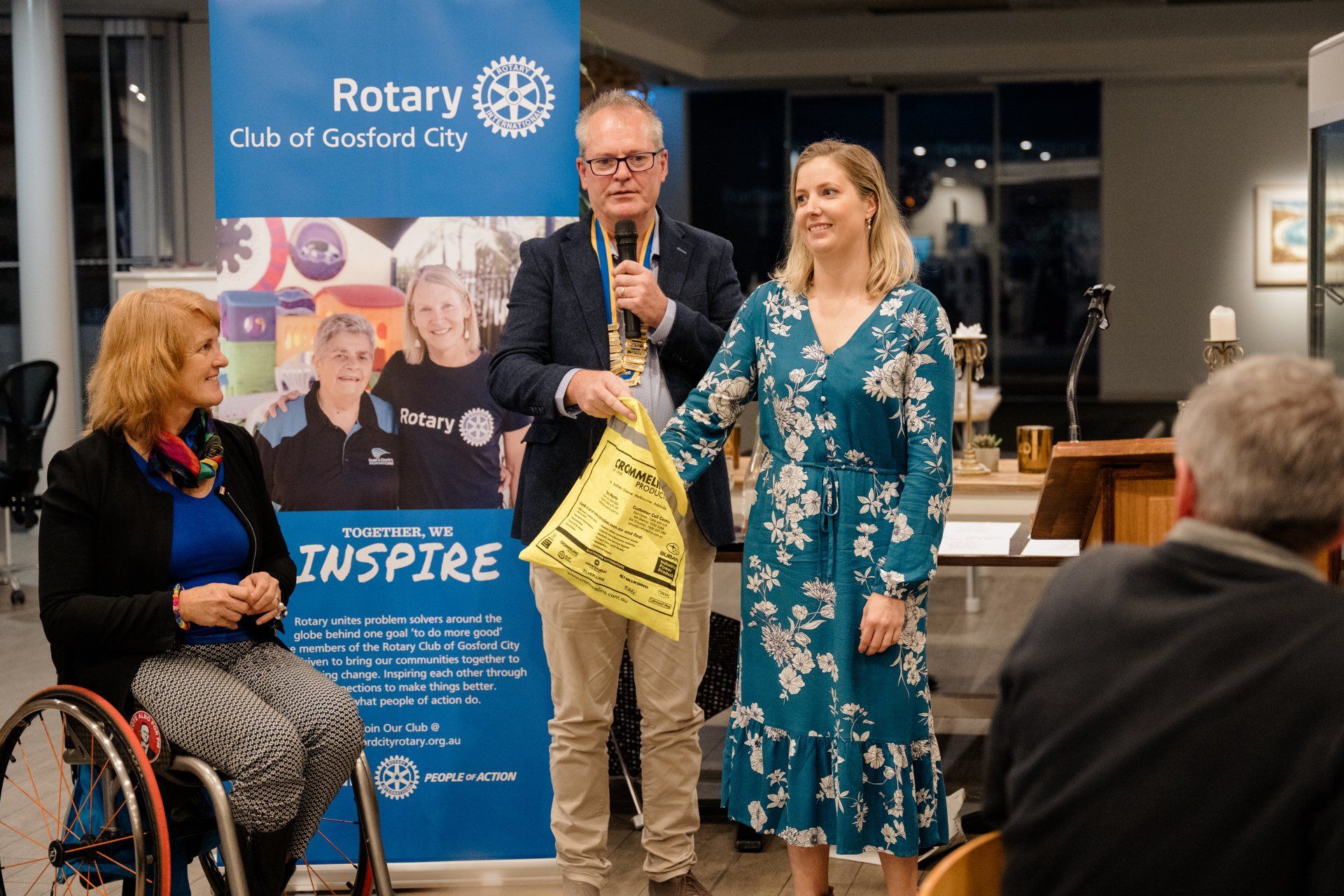 A group of people are standing in front of a rotary sign.