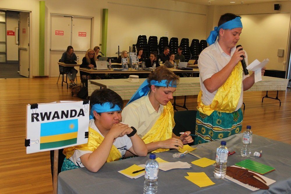 A group of people sitting at a table with a sign that says rwanda