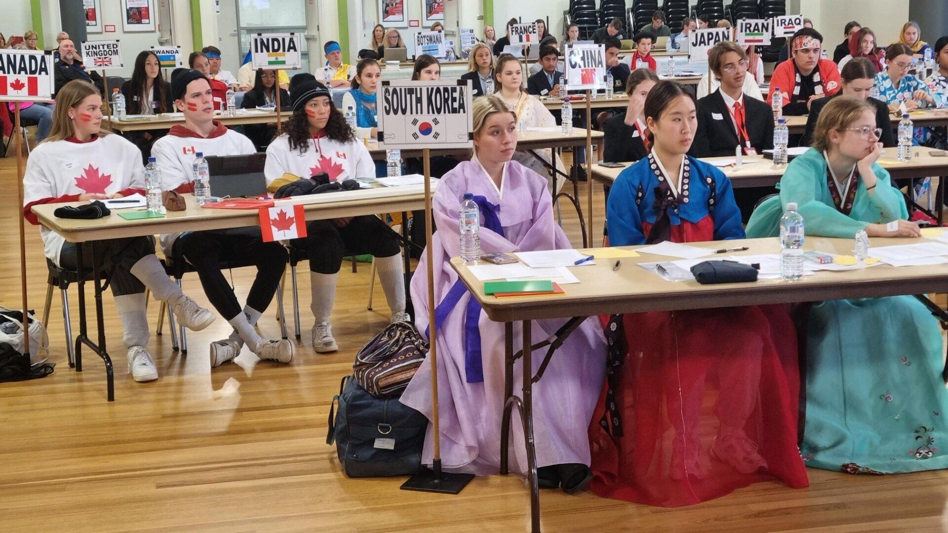 A group of people are sitting at tables in front of a sign that says south korea