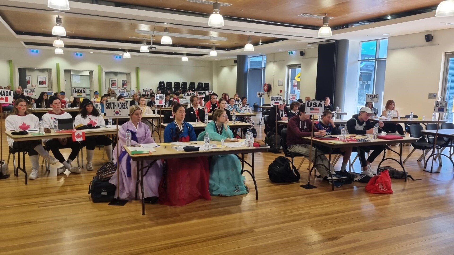 A group of people are sitting at tables in a large room.