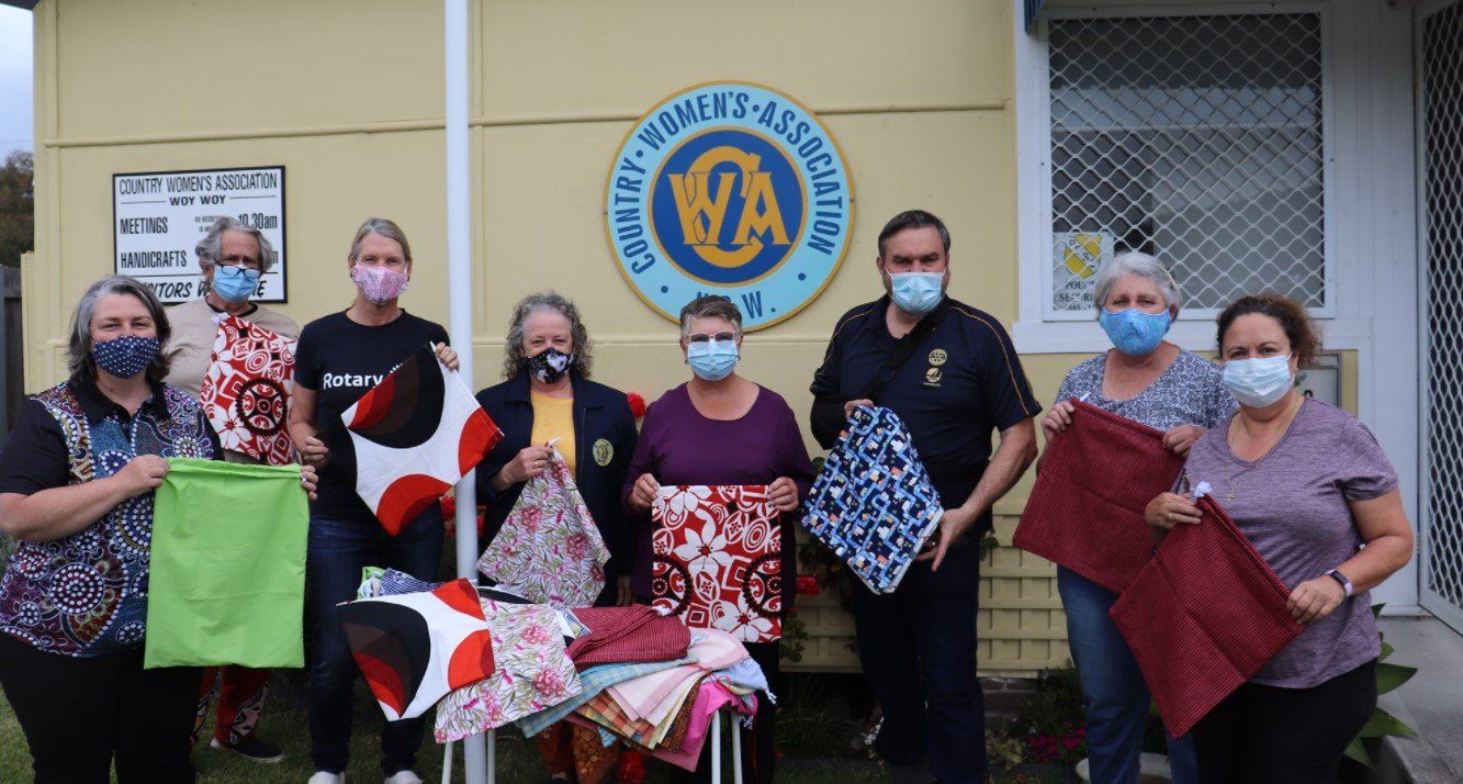 A group of people wearing face masks are holding blankets in front of a building.