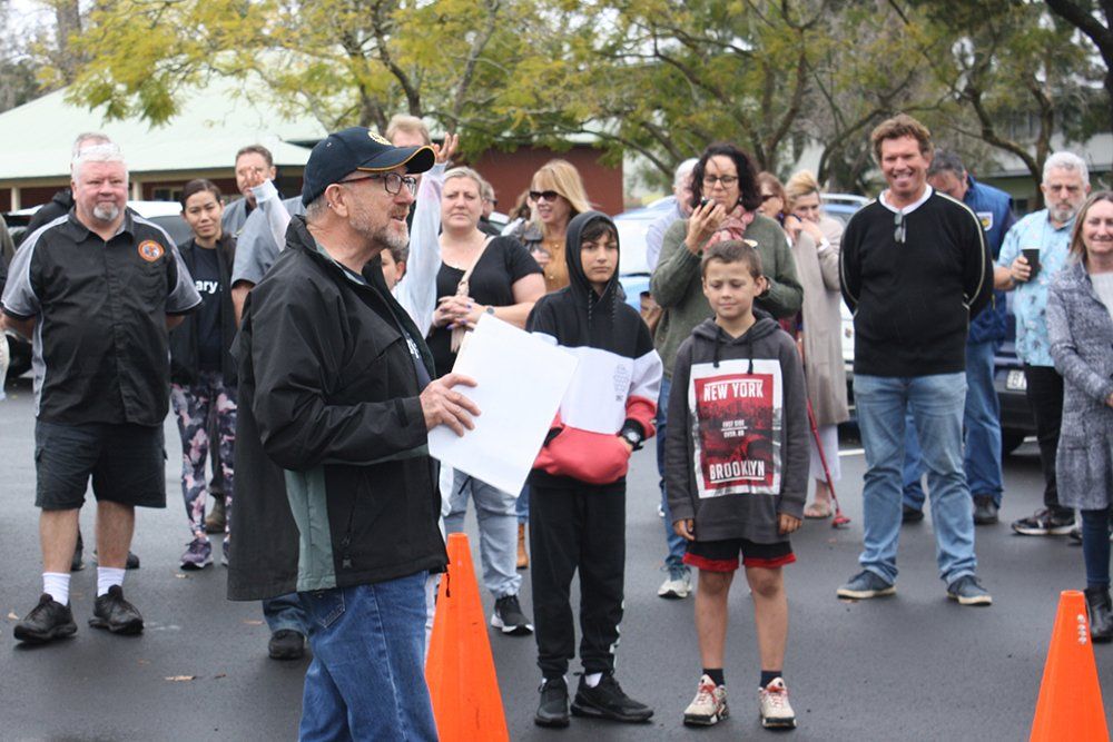 A man is standing in front of a crowd of people holding a sign.