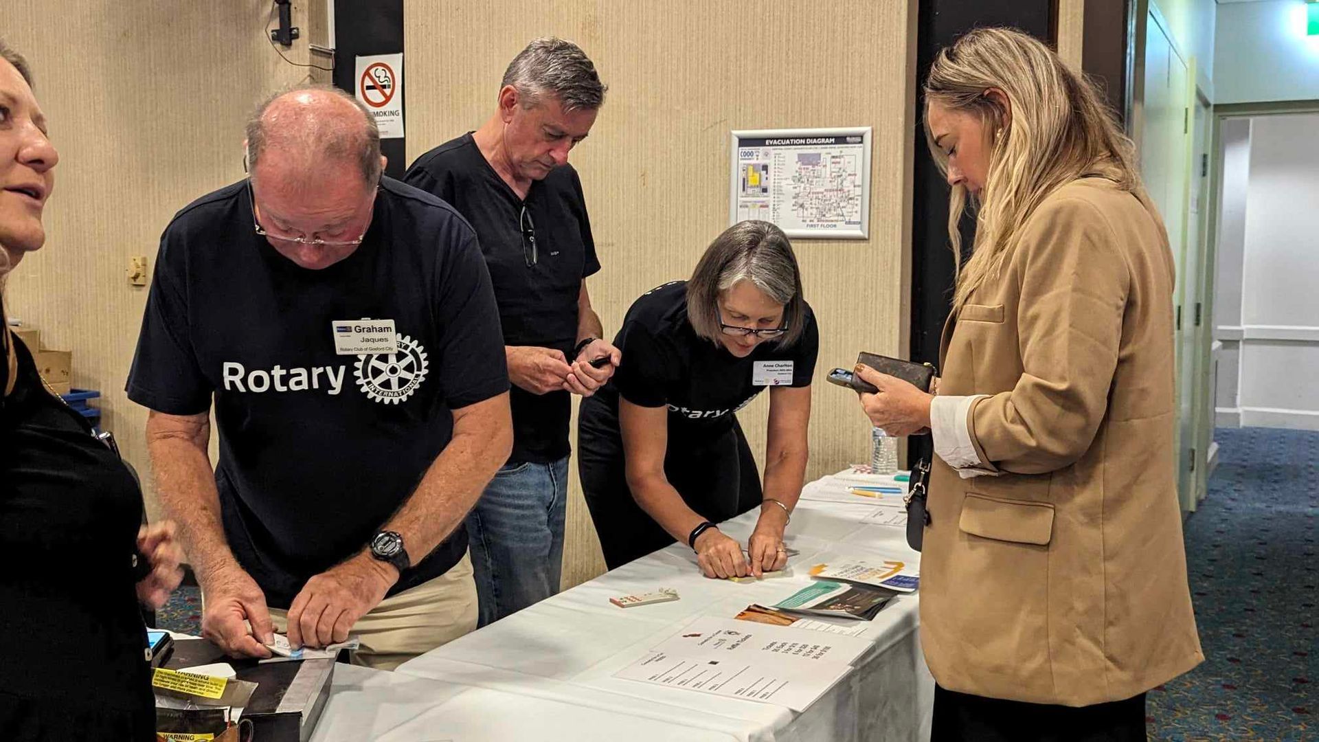 A group of people are standing around a table.