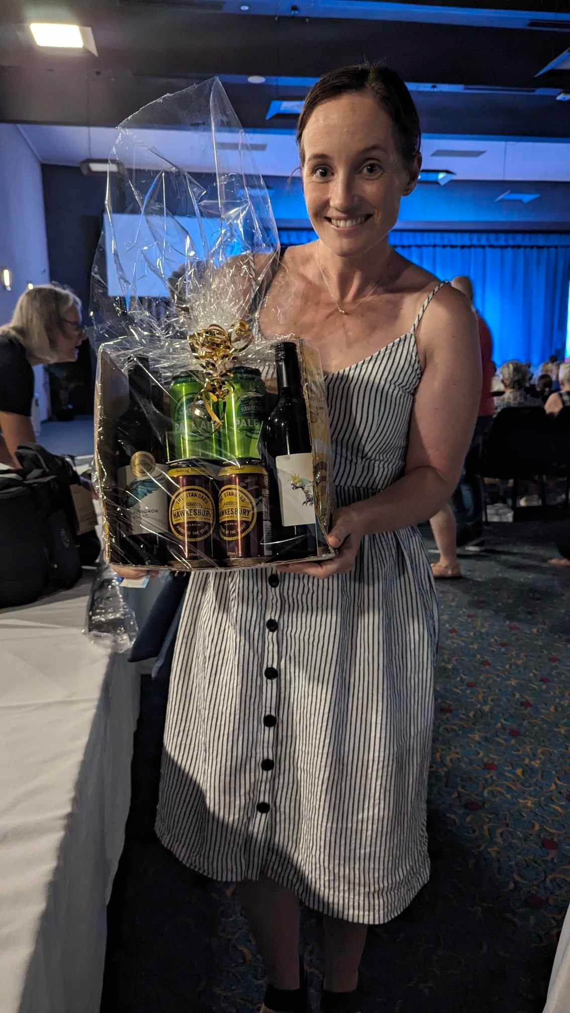 A woman in a dress is holding a basket of beer and wine.