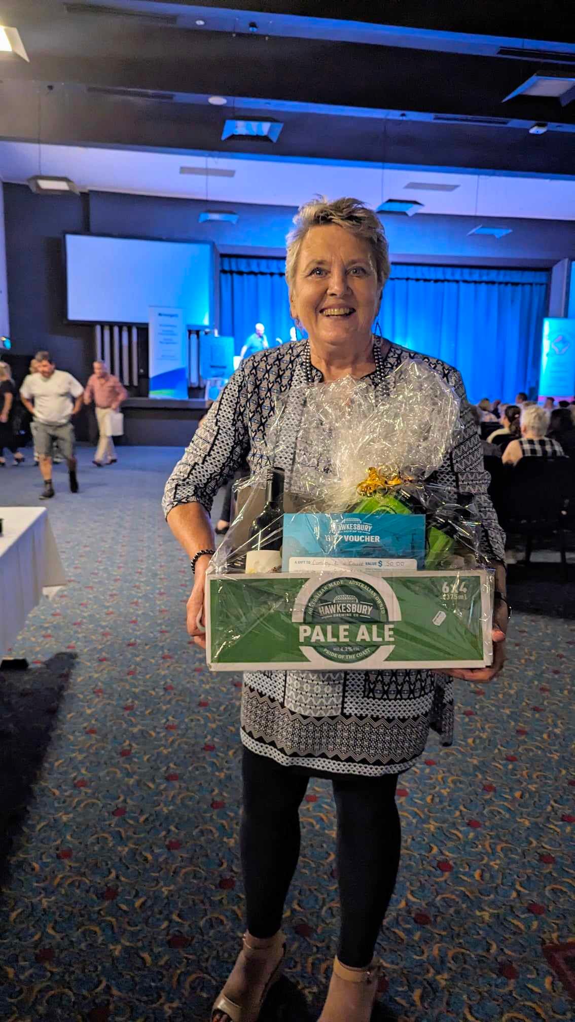 A woman is holding a box of beer in a room.