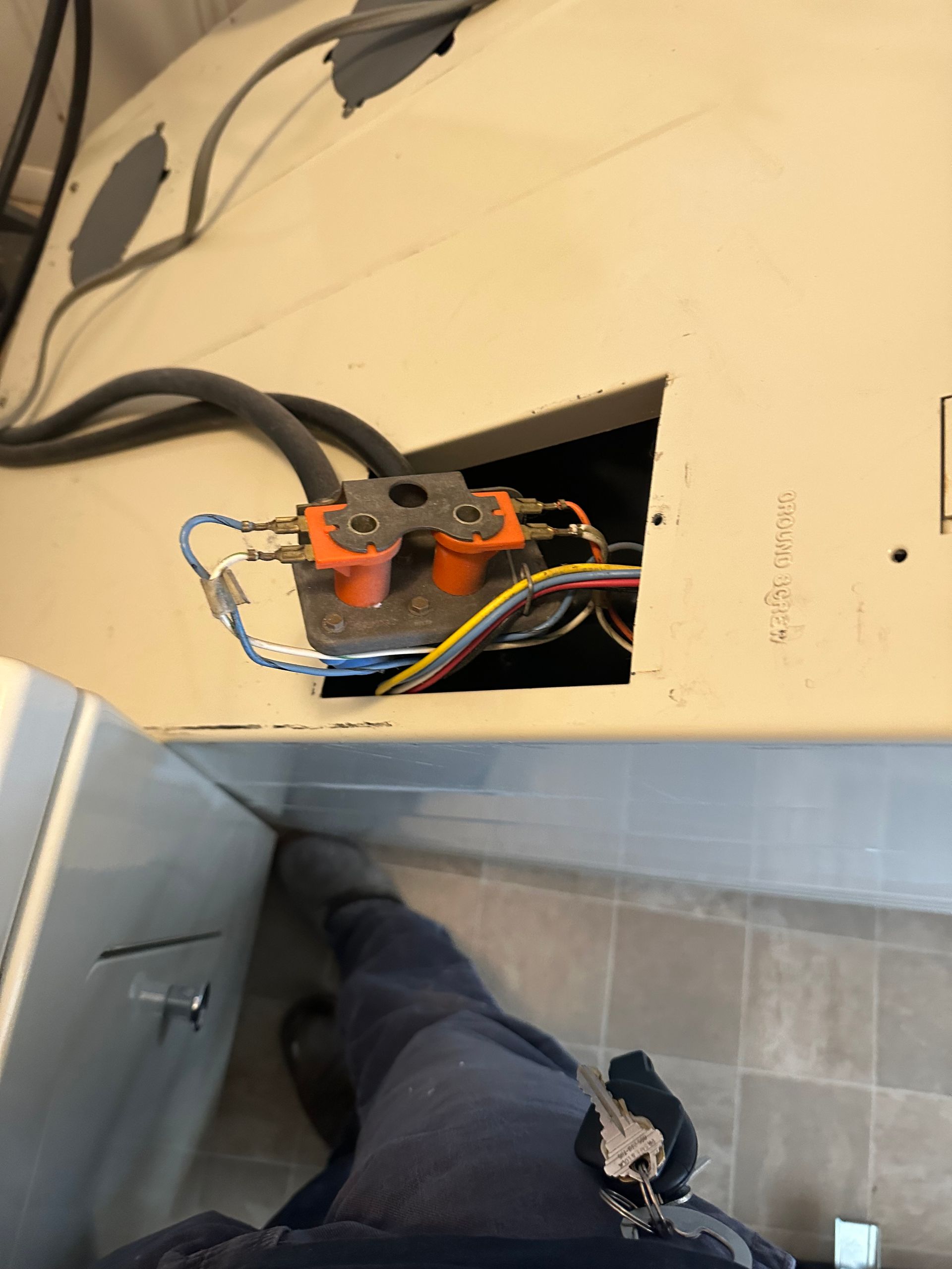 A person is standing next to a washer and dryer with a key in their pocket.