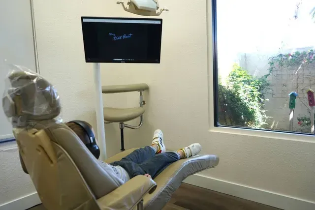 A child is laying in a dental chair in front of a window.