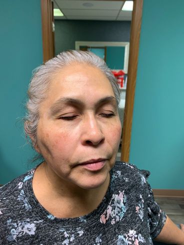 Person with eyes closed indoors, standing by a doorway in a teal-walled room.
