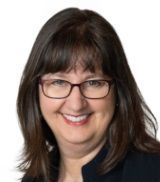 A woman wearing glasses and a black hair is smiling for the camera.