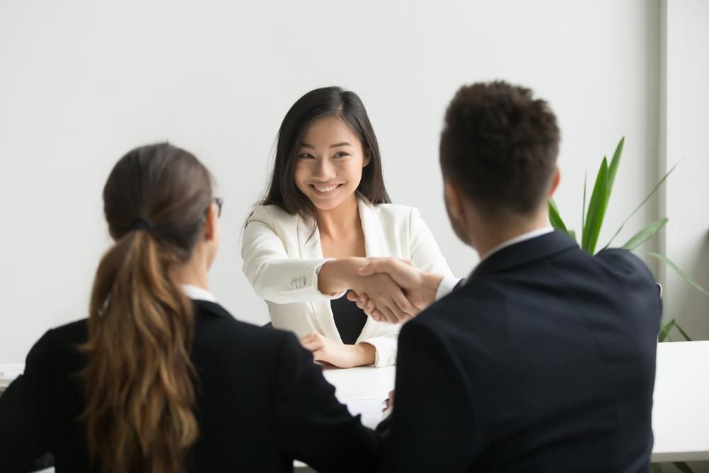 A Woman Is Shaking Hands With A Man And A Woman During A Job Interview — Active Ables Community Services In Logan, QLD
