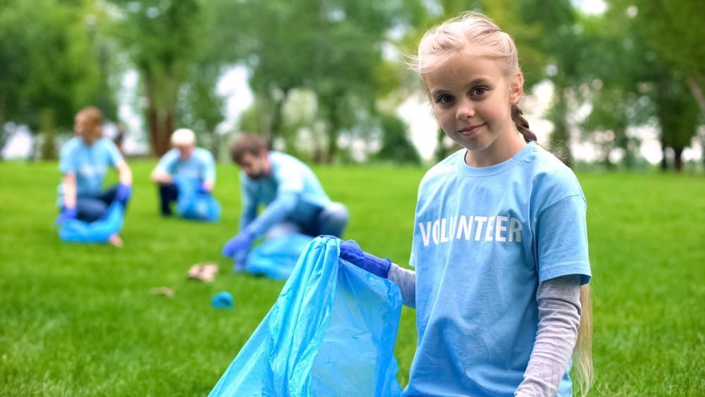 A Young Girl Is Holding A Blue Bag In A Park — Active Ables Community Services In Toowoomba, QLD