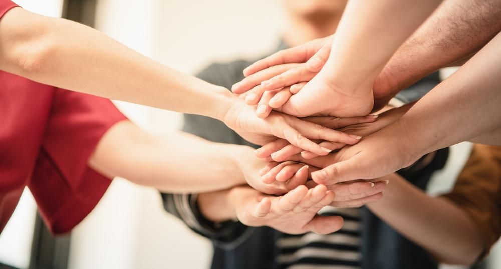 A Group Of People Are Putting Their Hands Together — Active Ables Community Services In Tamworth, NSW