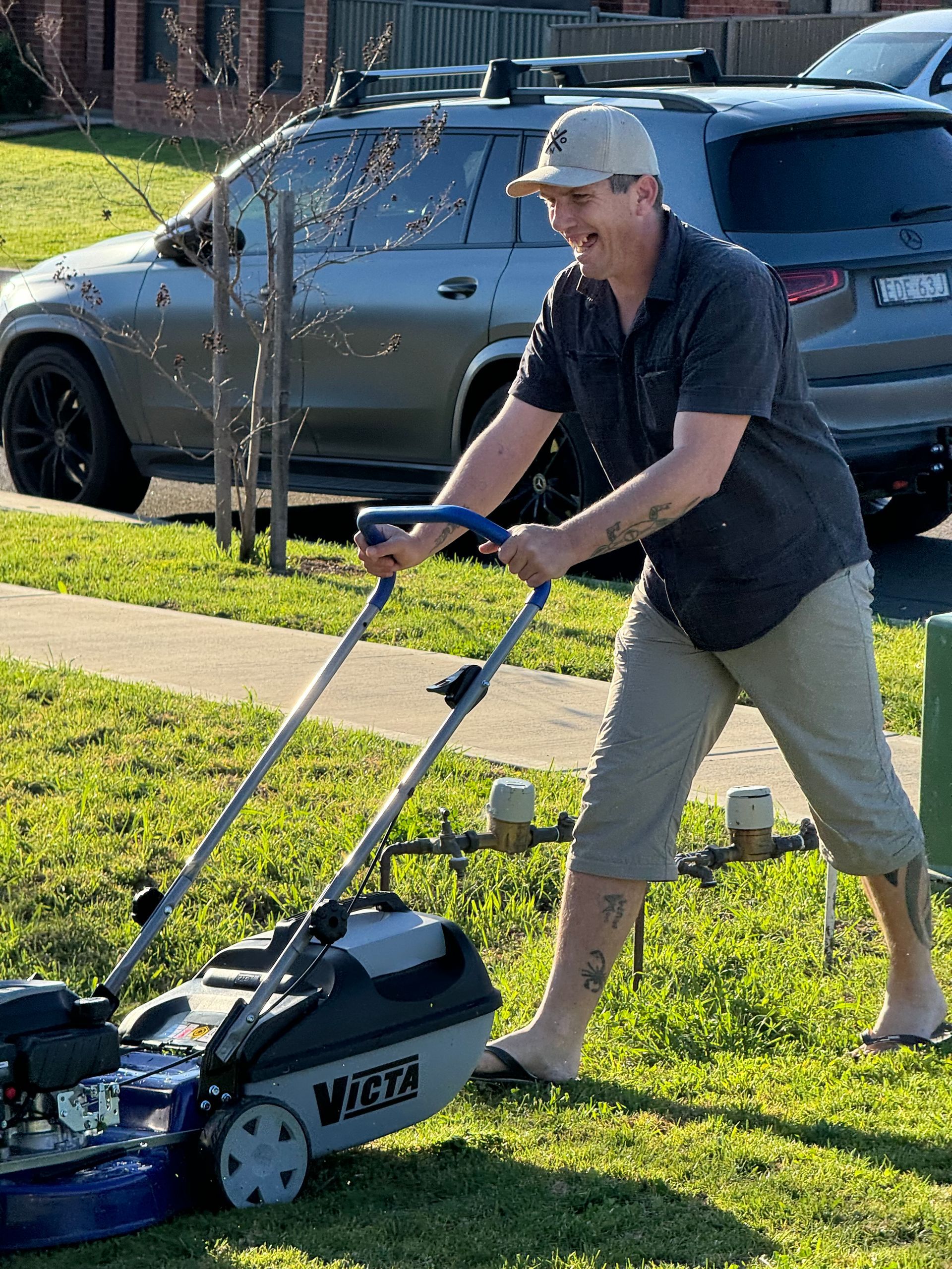 A Man Is Mowing The Grass With A Lawn Mower — Active Ables Community Services In Tamworth, NSW