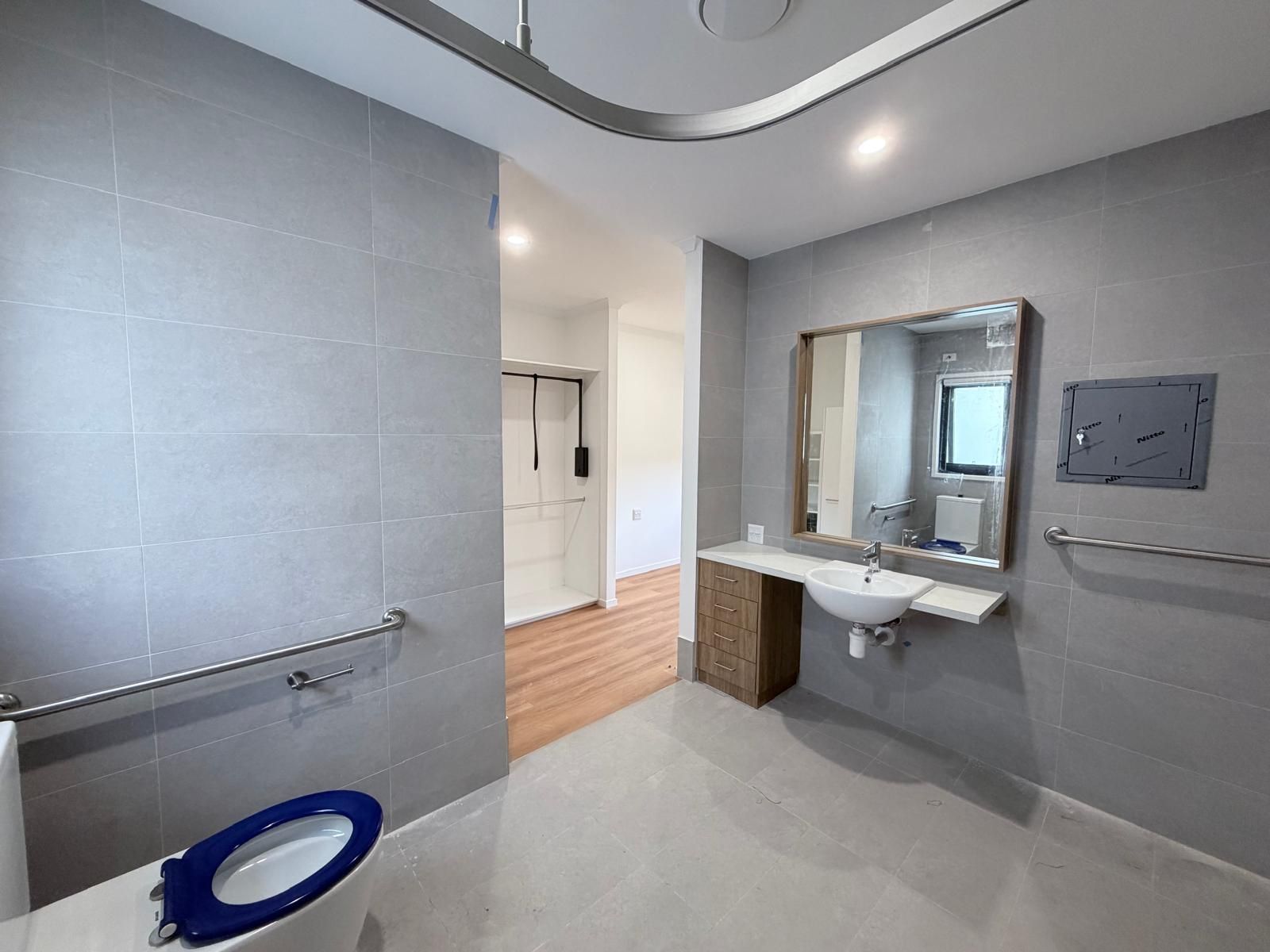 Modern accessible restroom with grab bars, sink, mirror, and tiled walls