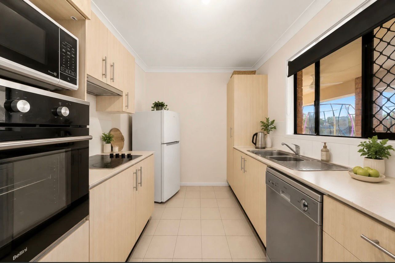 Bright modern kitchen with black appliances, beige cabinets, white fridge, and a window over the sink.