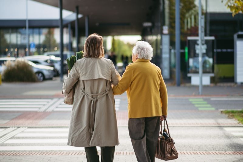 A Woman Is Helping an Older Woman Cross a Street — Active Ables Community Services In Tamworth, NSW