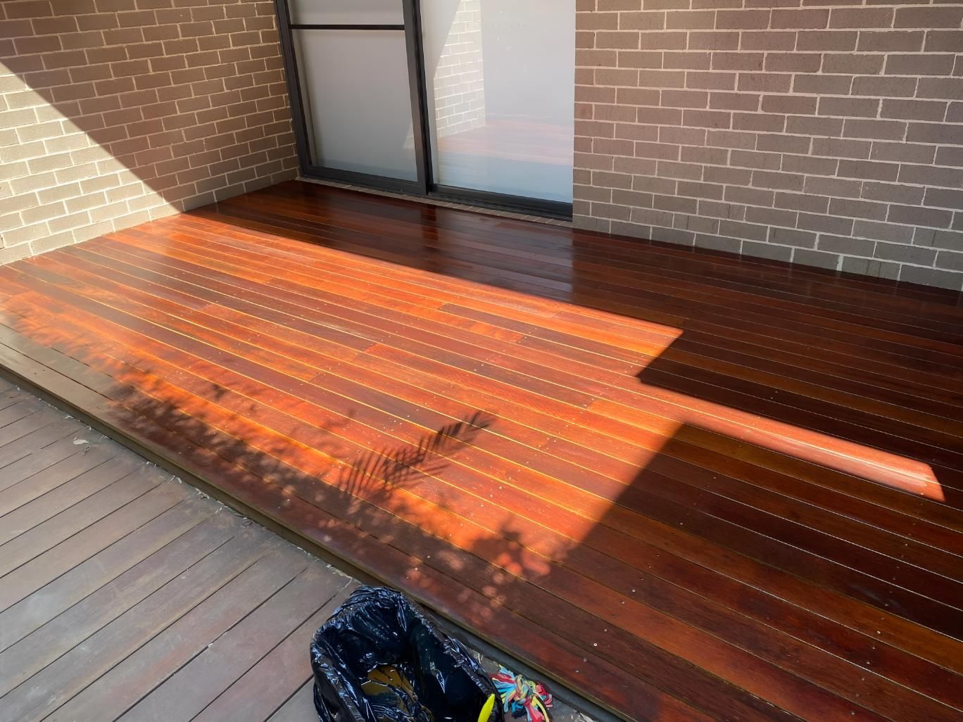 A Wooden Deck Is Sitting In Front Of A Brick Building — Coolangatta Floor Sanding In Shoalhaven Heads, NSW