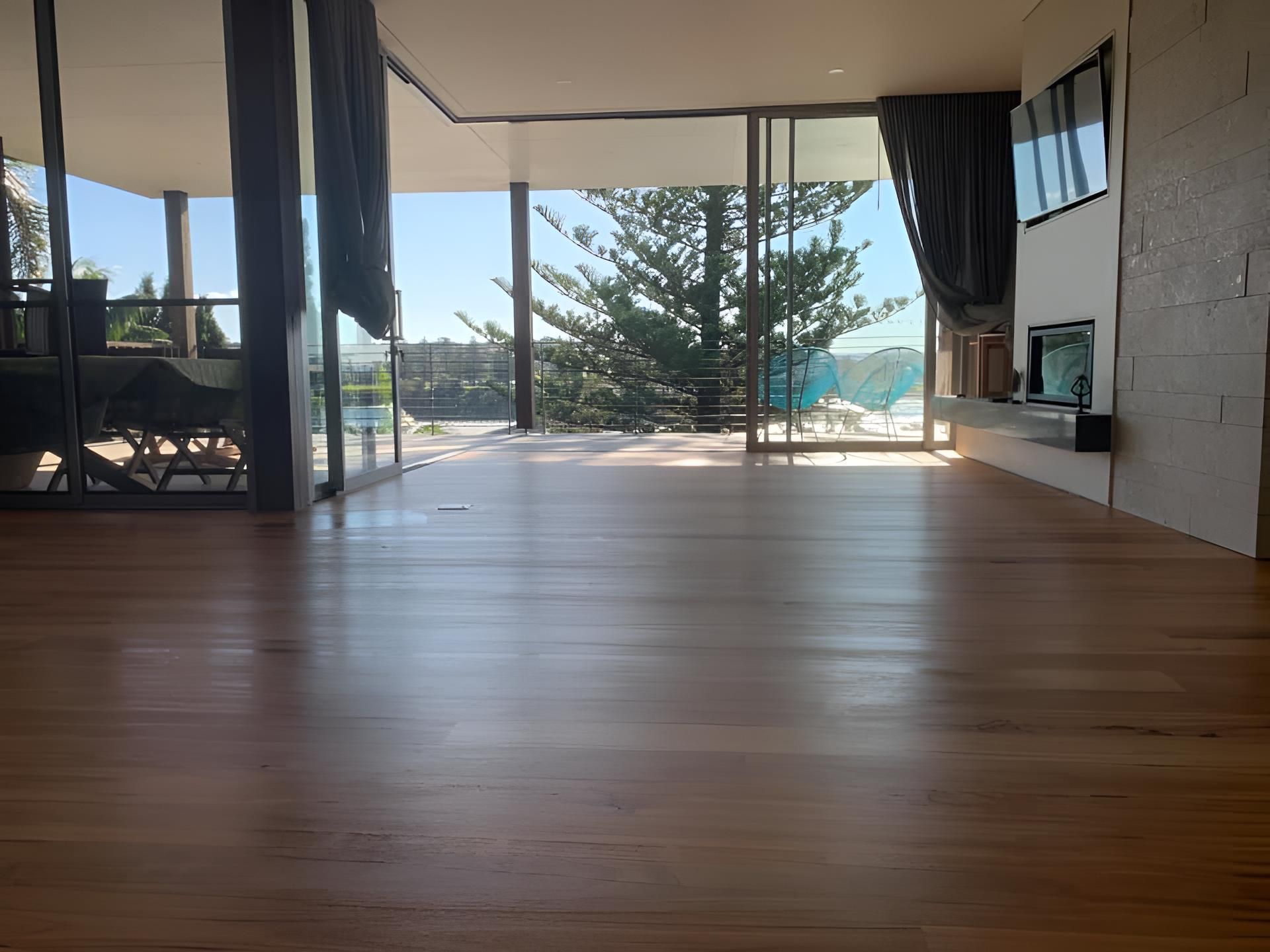 A living room with a wooden floor and a lot of windows — Coolangatta Floor Sanding In Shoalhaven Heads, NSW