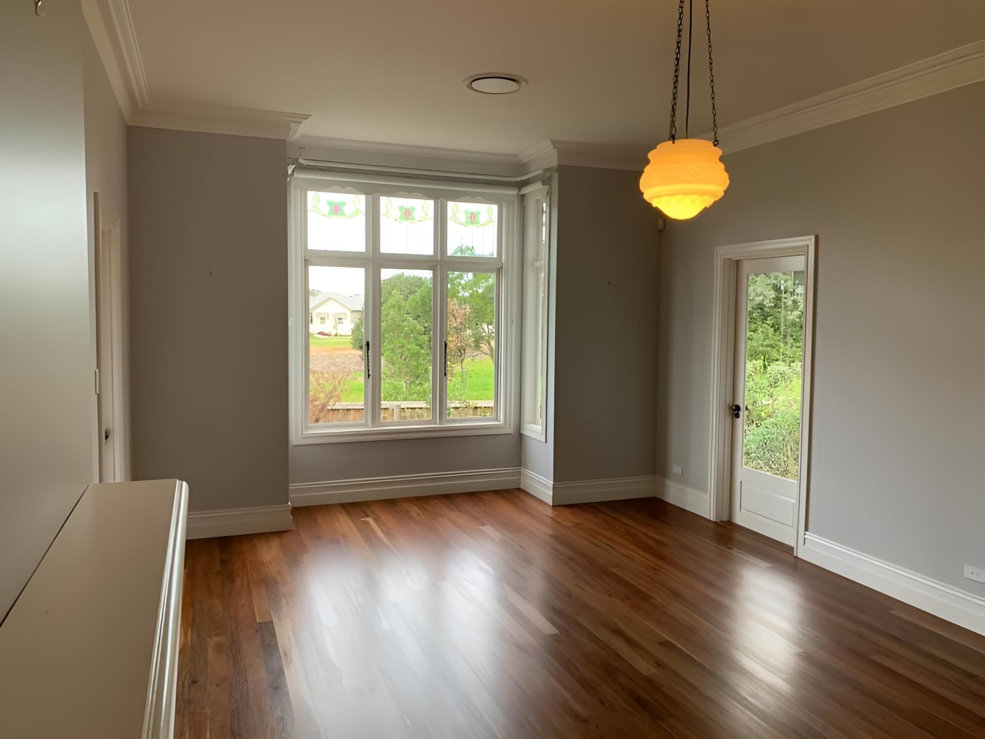 An Empty Living Room With Hardwood Floors And A Large Window — Coolangatta Floor Sanding In Huskisson, NSW