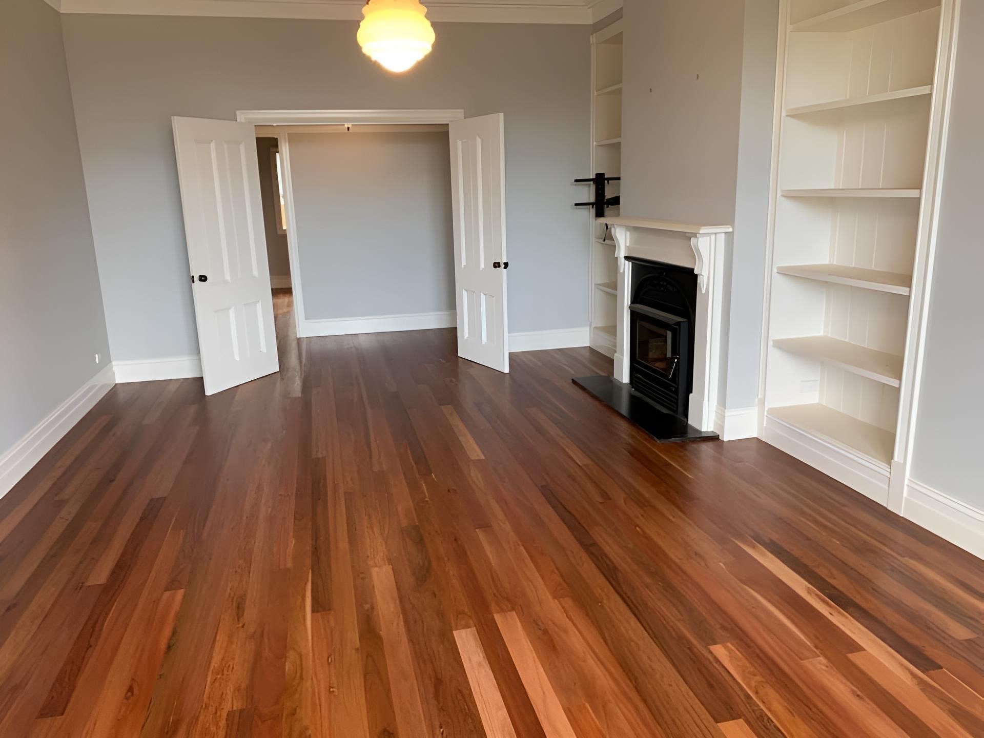 An Empty Living Room With Hardwood Floors And A Fireplace — Coolangatta Floor Sanding In Huskisson, NSW