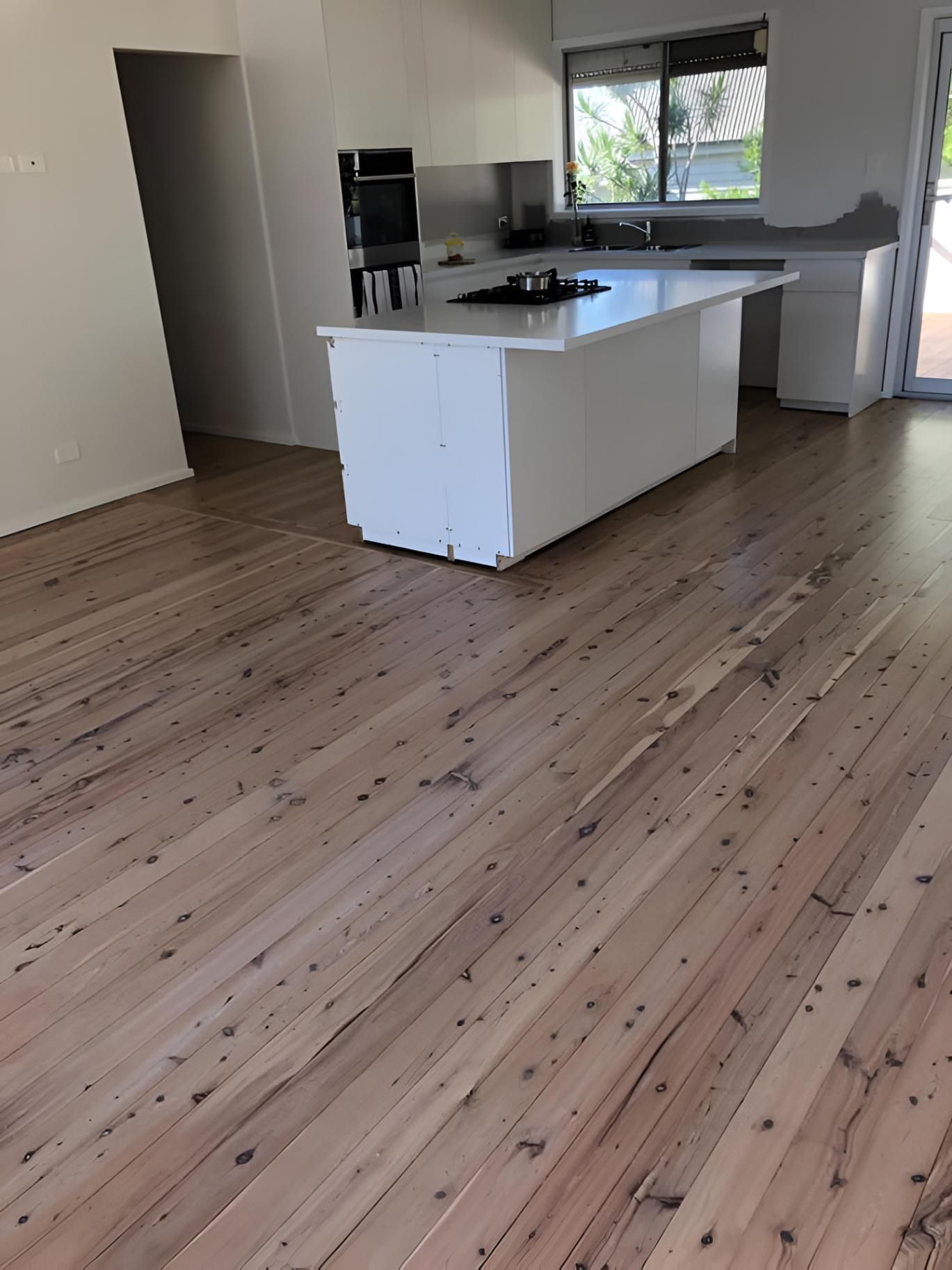 A Kitchen With A Wooden Floor And A White Island — Coolangatta Floor Sanding In Shoalhaven Heads, NSW