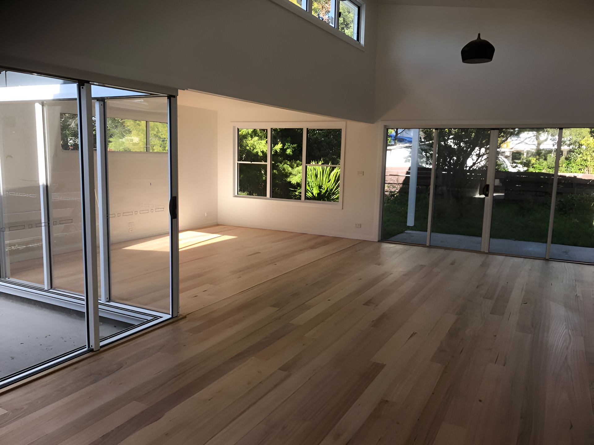 A Large Empty Room With Lots Of Windows And Wooden Floors — Coolangatta Floor Sanding In Shoalhaven Heads, NSW
