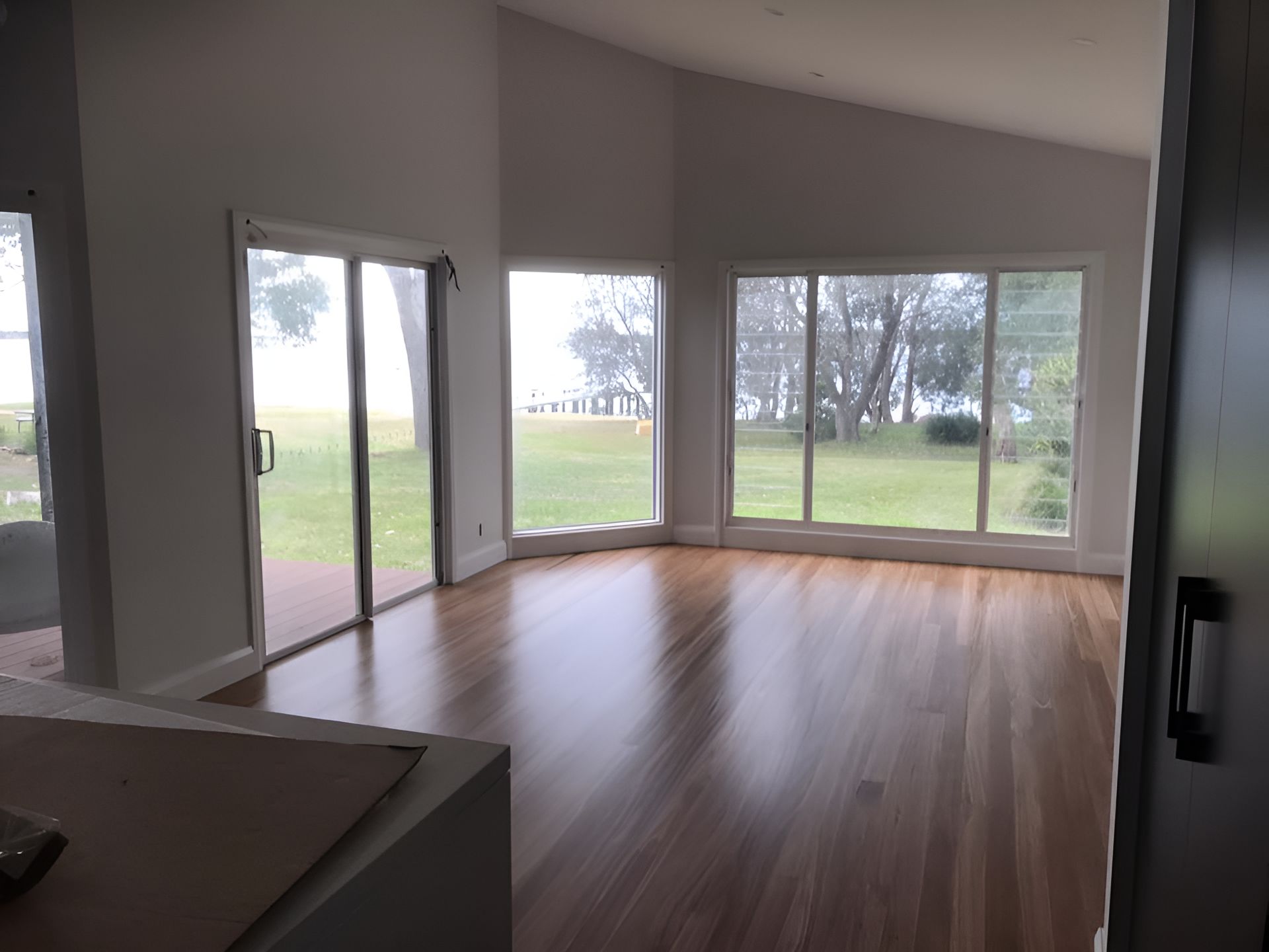 An Empty Living Room With Hardwood Floors And Lots Of Windows — Coolangatta Floor Sanding In Shoalhaven Heads, NSW