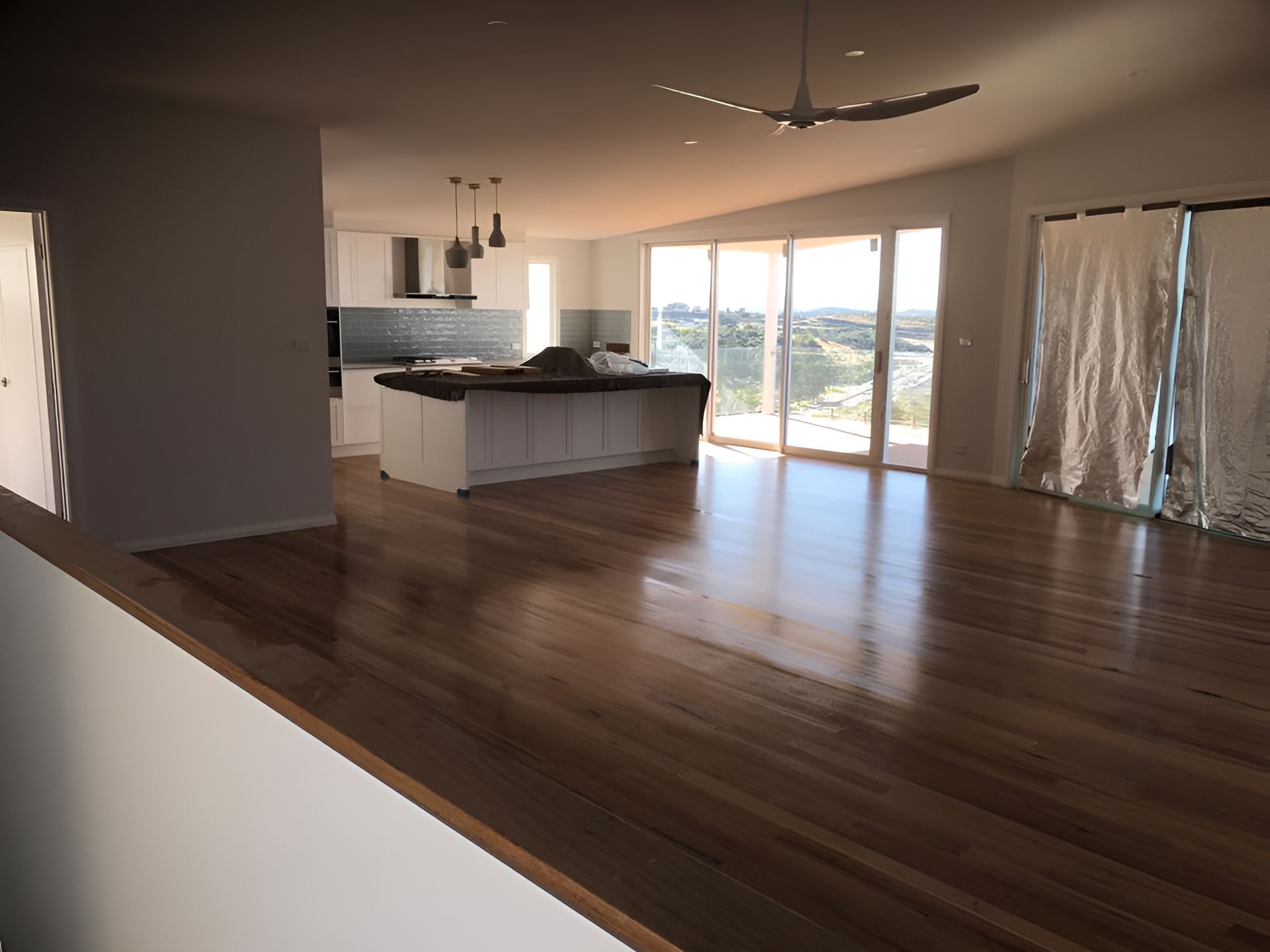 An Empty Room With Hardwood Floors And A Ceiling Fan — Coolangatta Floor Sanding In Shoalhaven Heads, NSW
