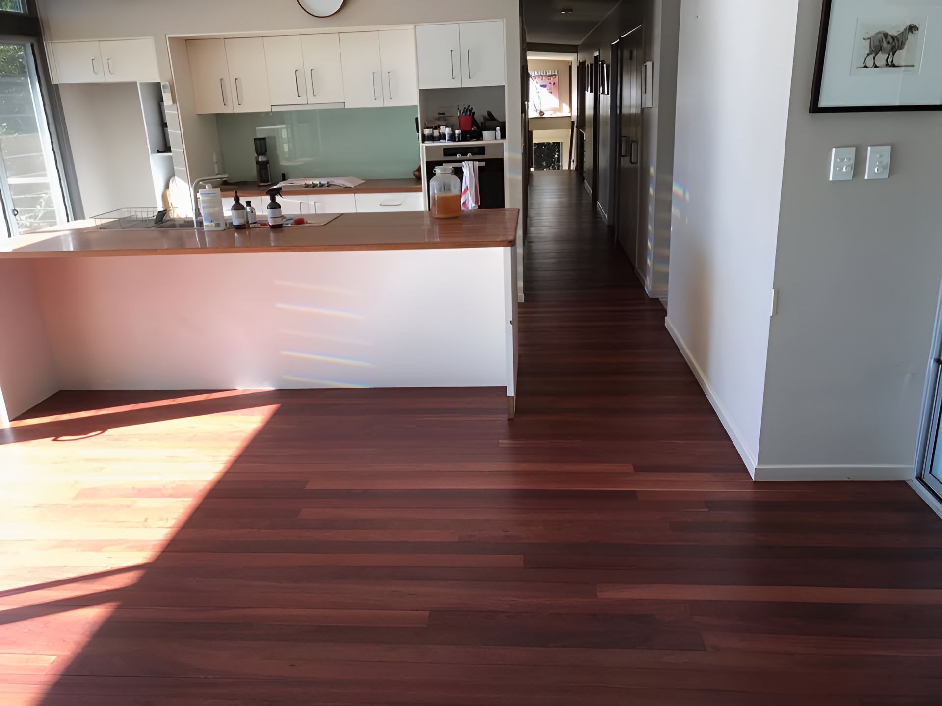 A Kitchen With A Wooden Floor And White Cabinets — Coolangatta Floor Sanding In Shoalhaven Heads, NSW
