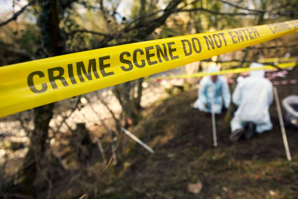 Il nastro giallo delimita l'area della scena del crimine. Gli investigatori della scientifica in tuta bianca stanno raccogliendo prove all'aperto.
