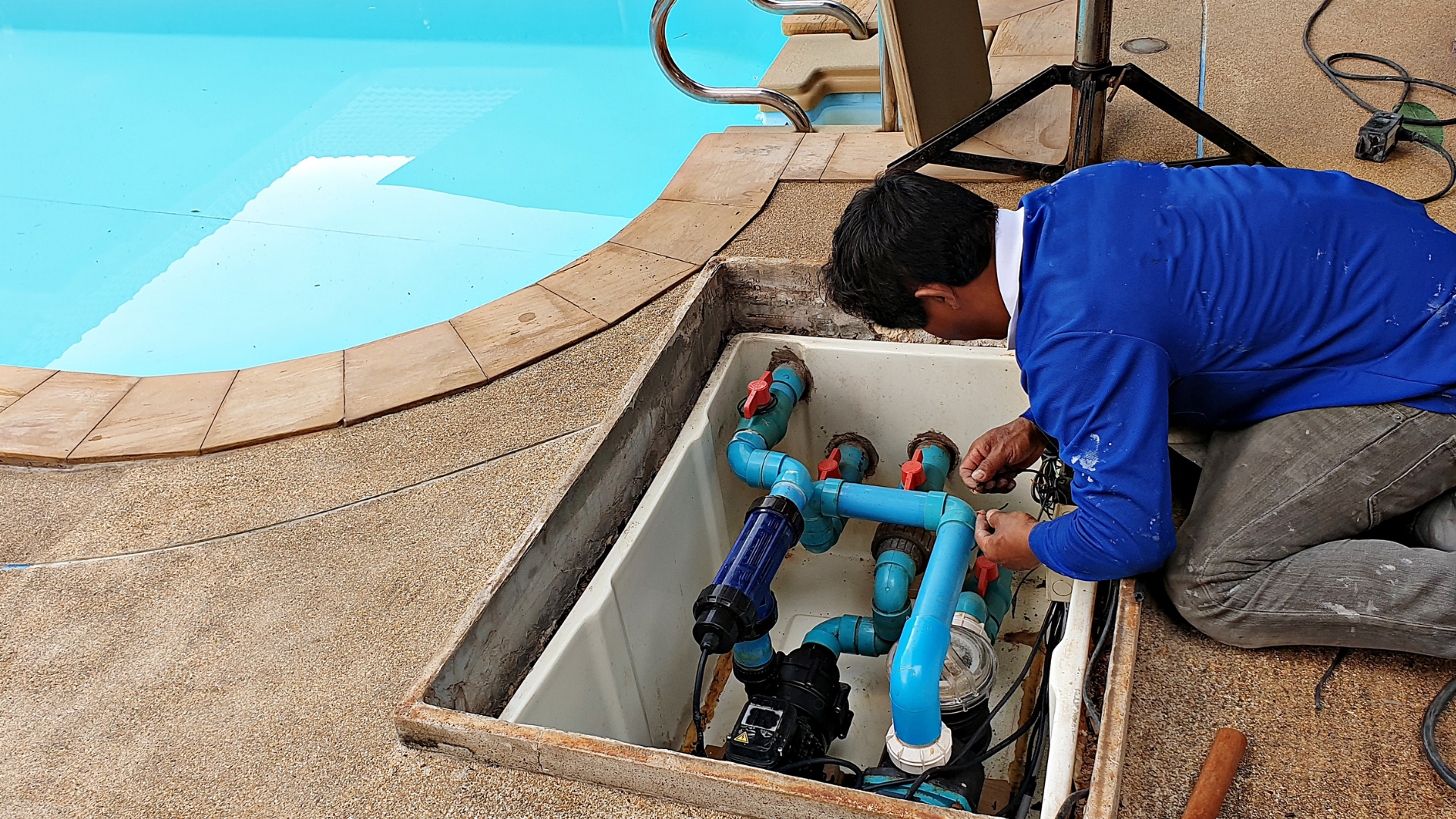 Professional pool repair technician fixing pool plumbing equipment, ensuring the pool's filtration and pump systems are in working order.