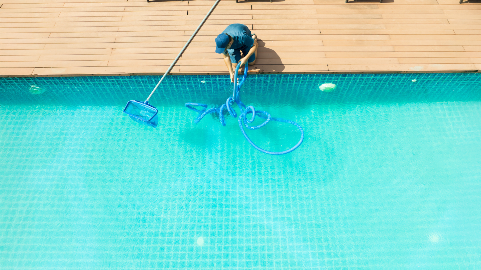 A pool maintenance worker untangling the hose of a pool vacuum to clean the pool, ensuring proper maintenance and water quality.