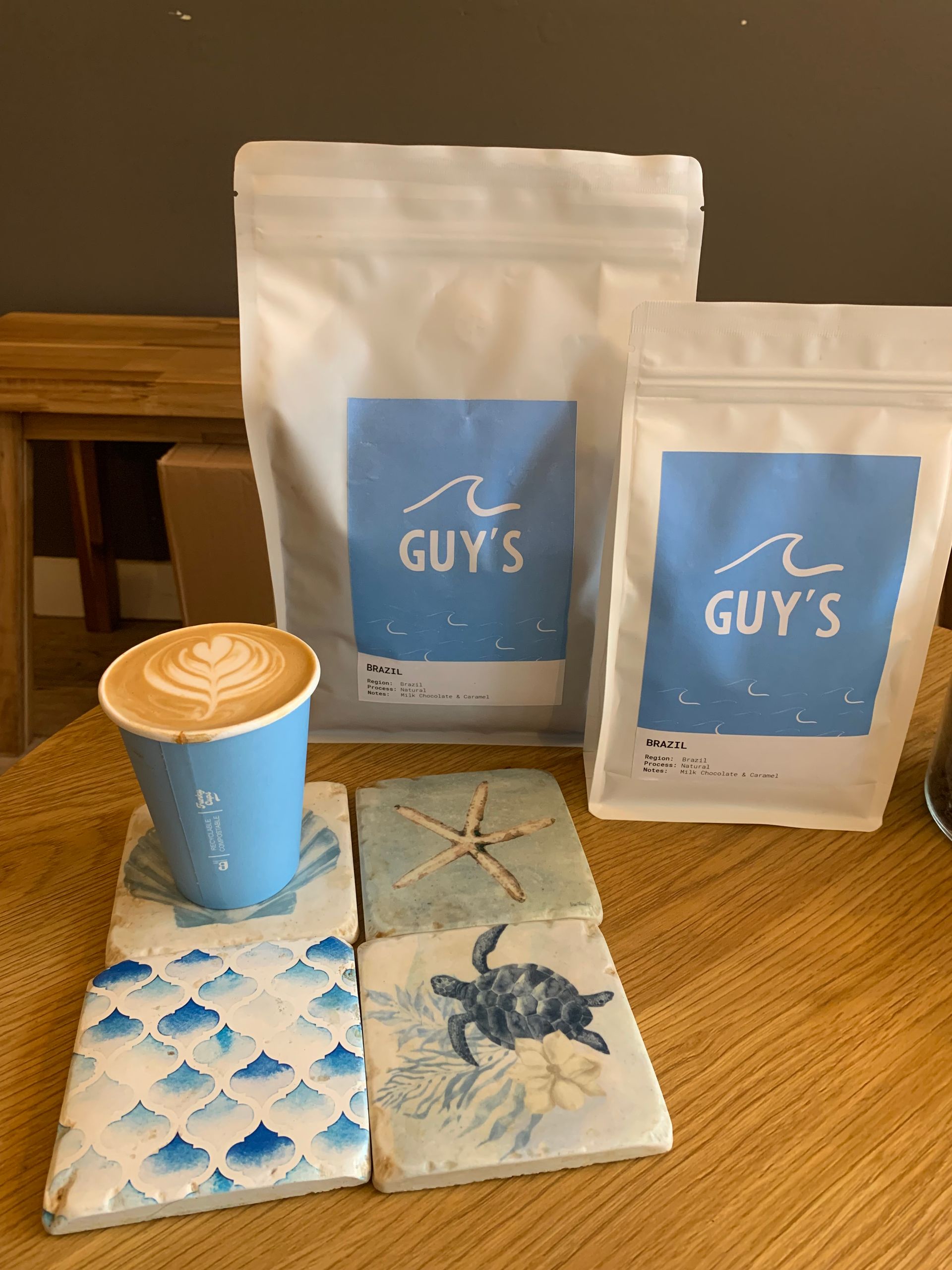 Coffee cup on coasters, bags of coffee labeled 