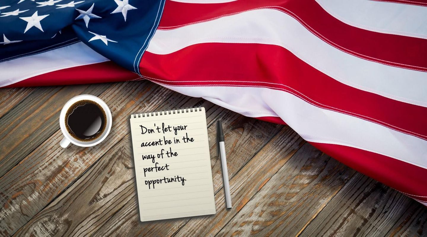an american flag is laying on a wooden table next to a cup of coffee and a notepad