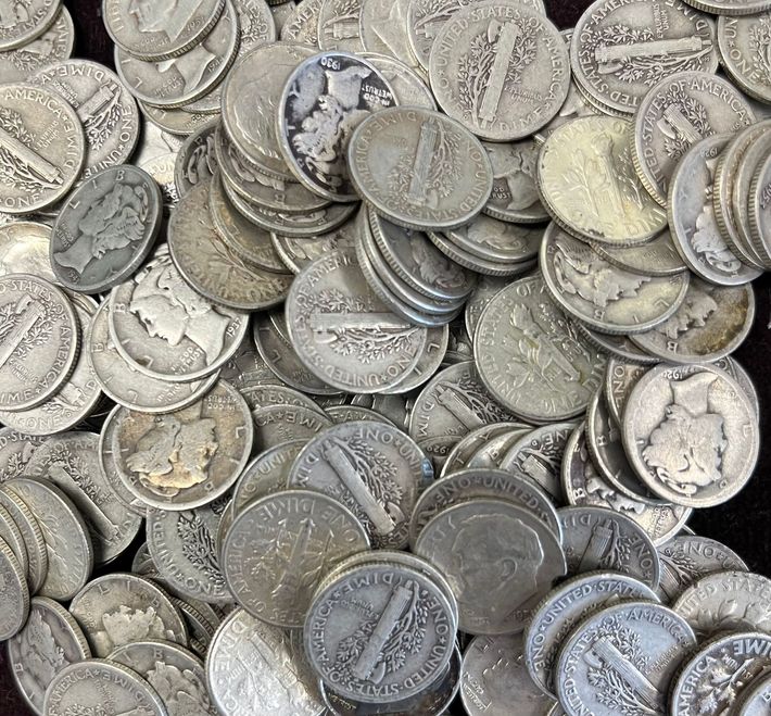 A wooden table with coins and bracelets on it