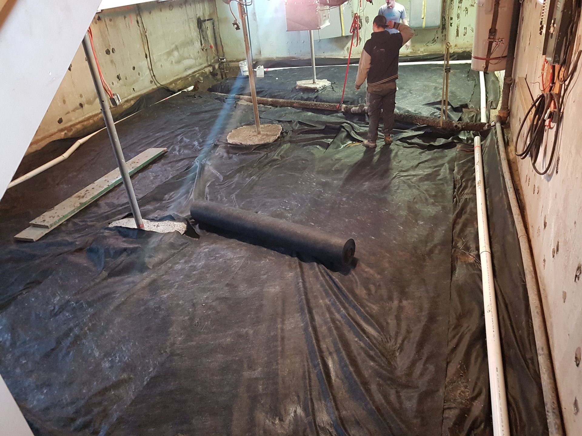 Un homme se tient debout sur une bâche noire dans une pièce.