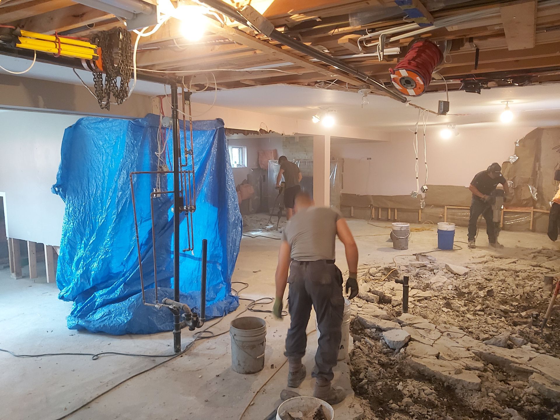 Un homme se tient debout dans une pièce avec une bâche bleue sur le sol.