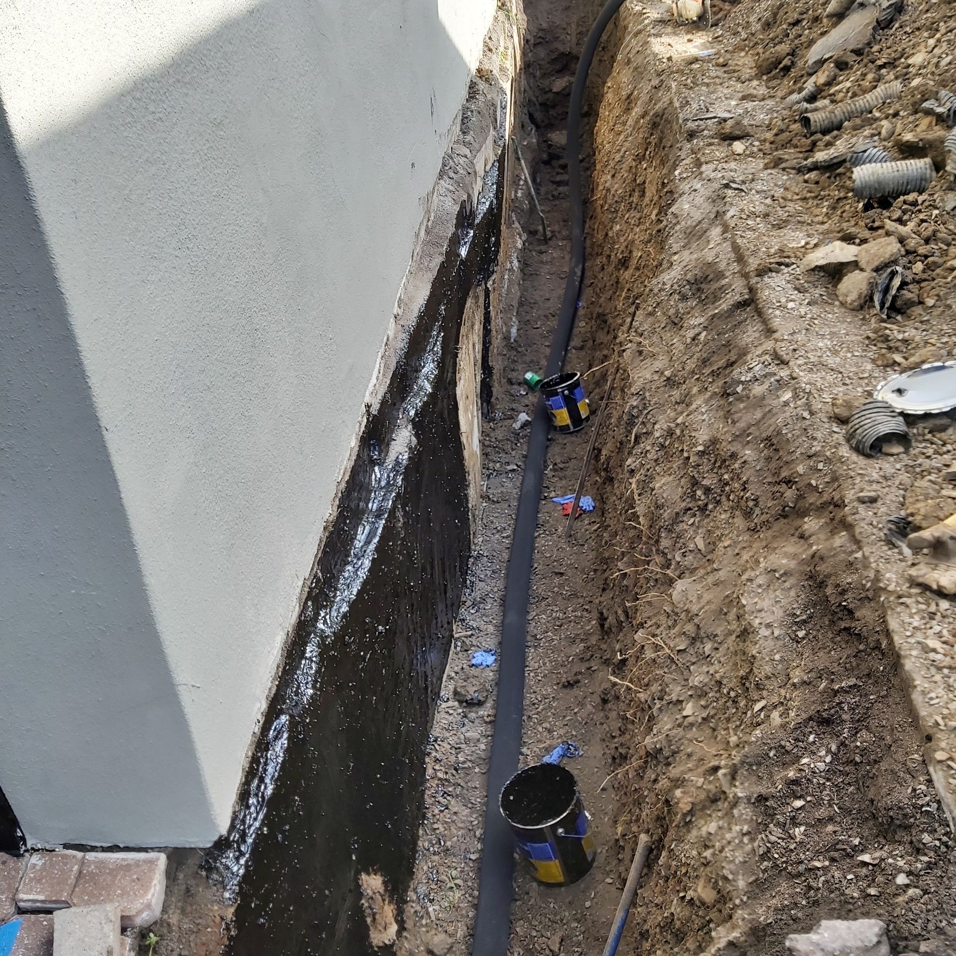 Un seau est posé dans la terre à côté d'un mur.