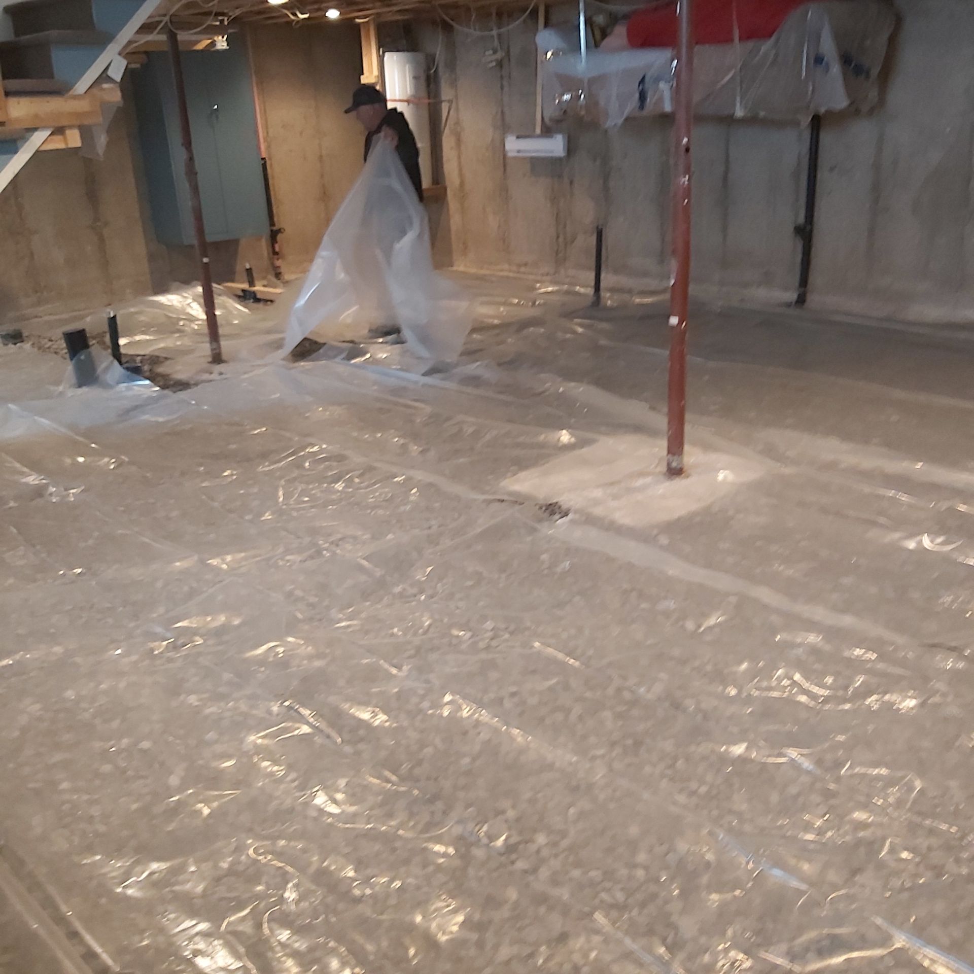 Un homme en combinaison de protection marche dans un sous-sol recouvert de plastique