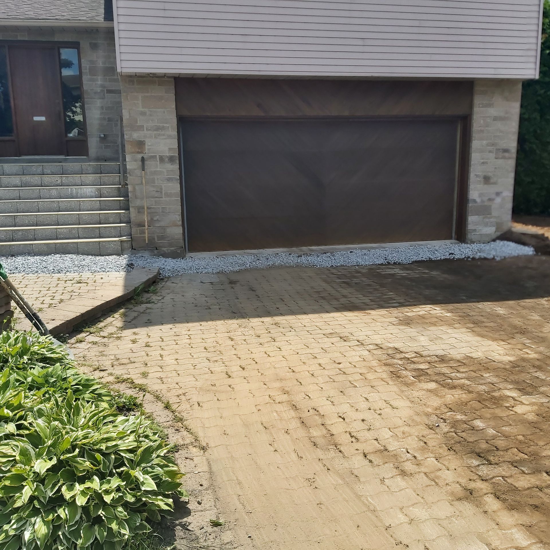 Une maison avec une porte de garage marron et une allée en briques