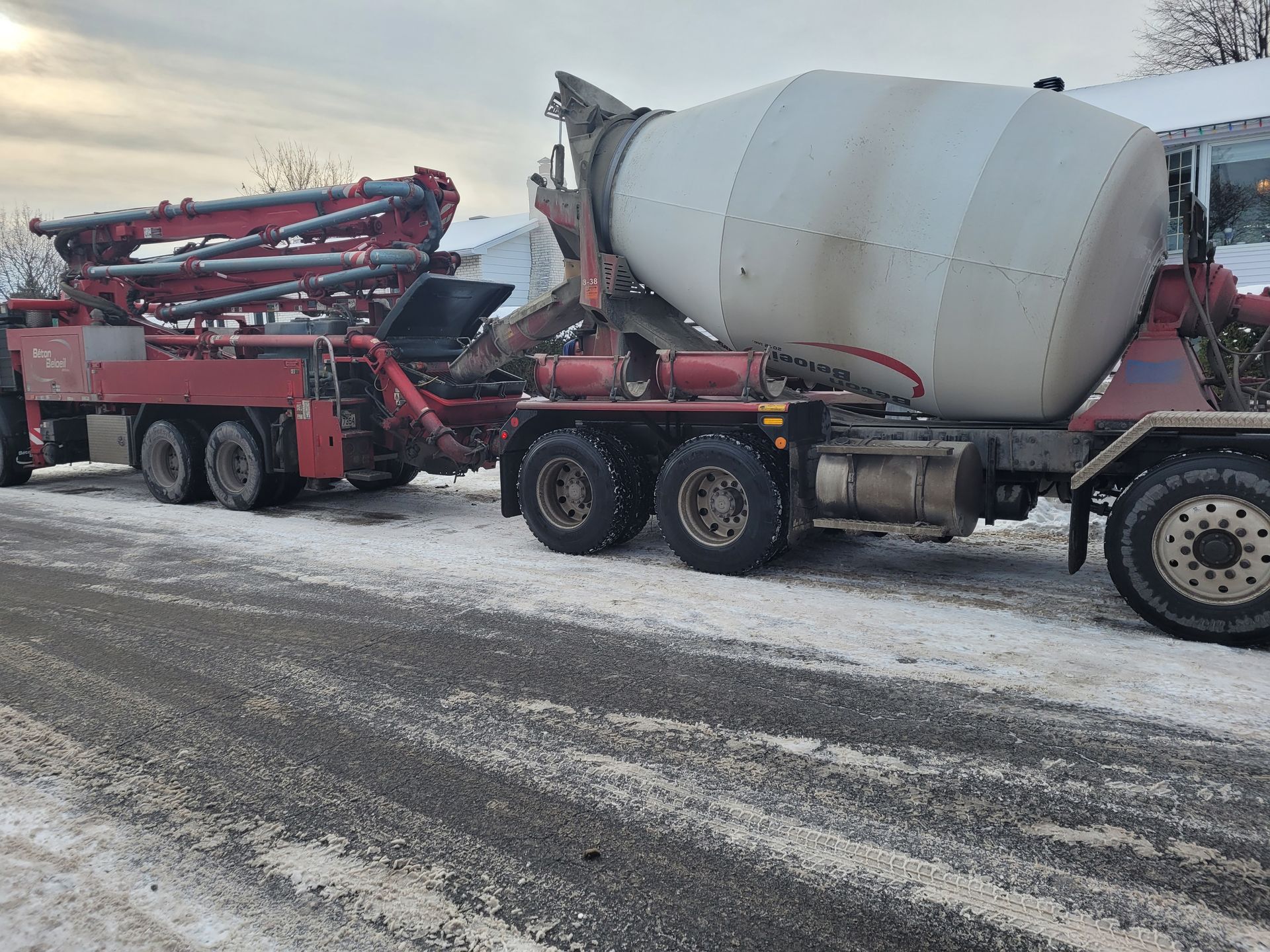 Un camion malaxeur à béton est garé sur le bord de la route sous la neige.