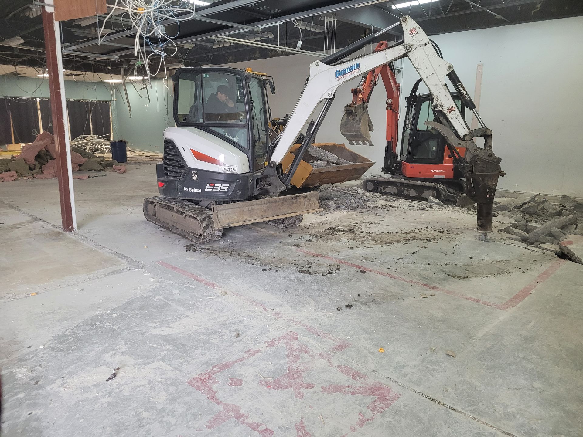 Deux excavatrices travaillent dans un bâtiment vide.