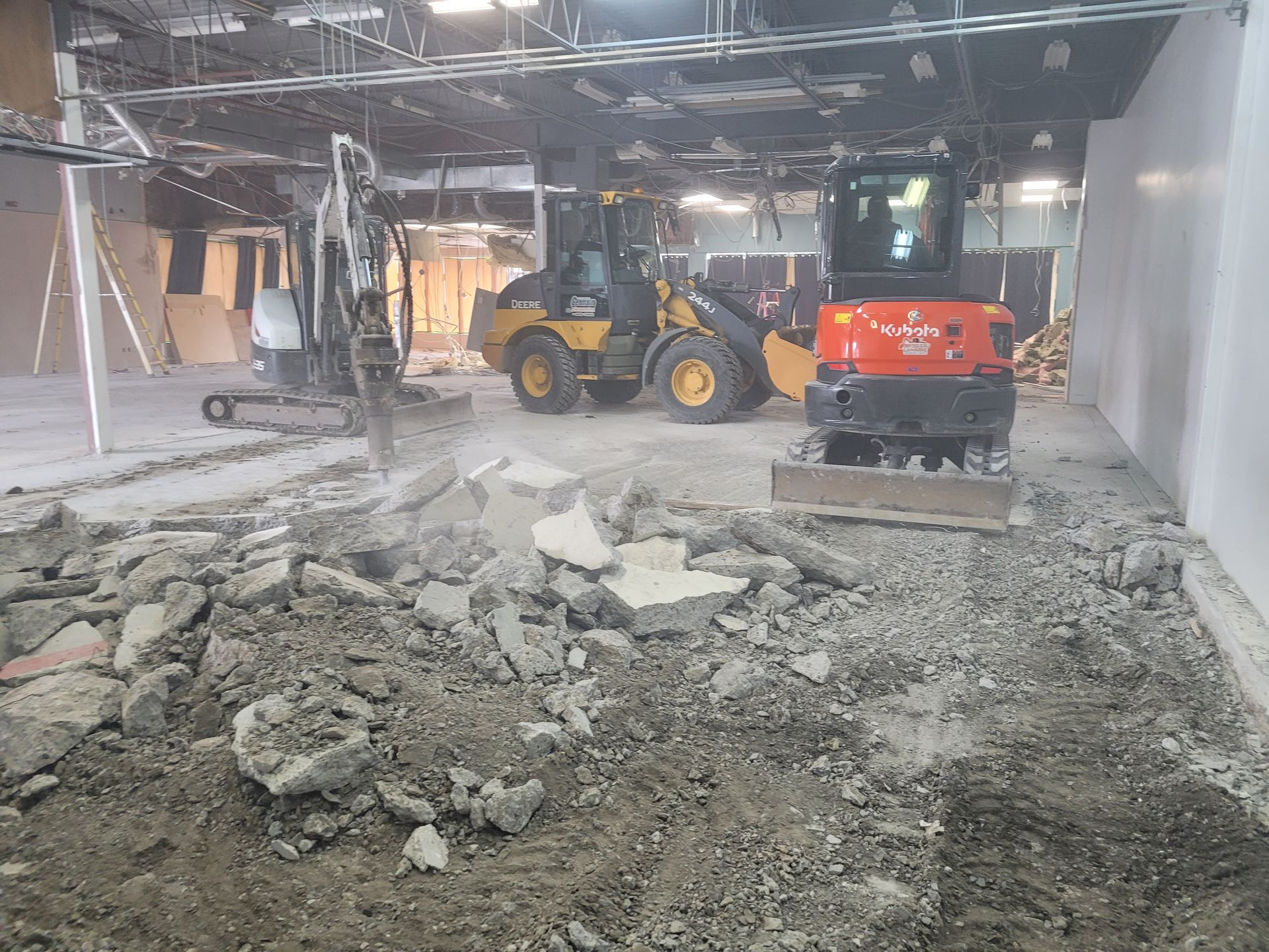 Un bulldozer et une pelle rétrocaveuse travaillent dans un bâtiment en construction.