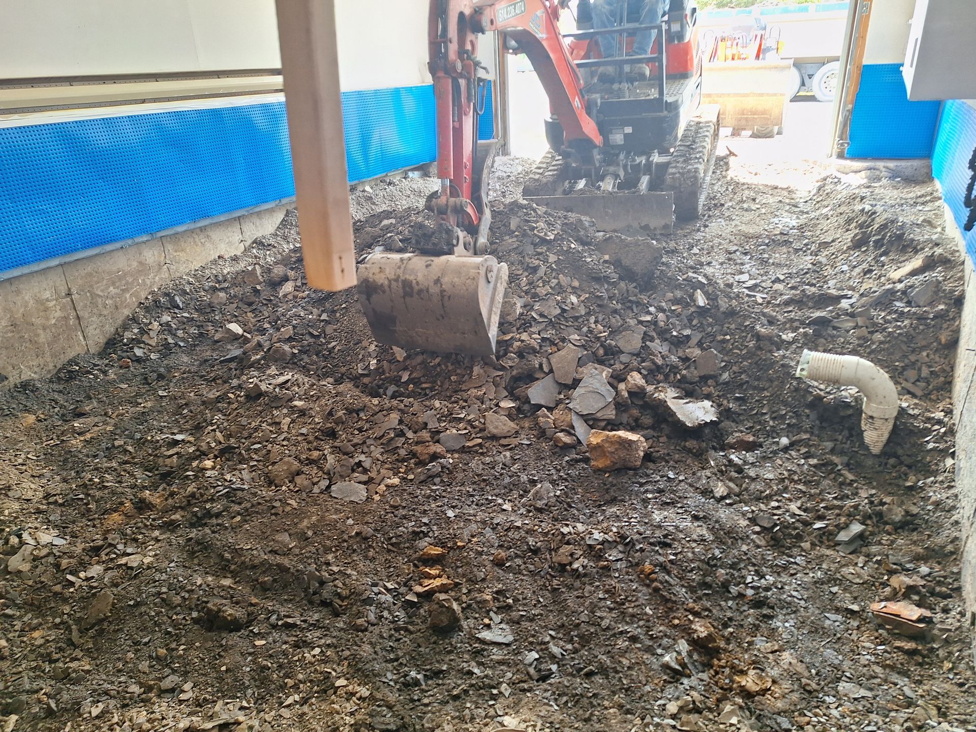 Une personne utilise une petite excavatrice pour creuser un trou dans le sol.