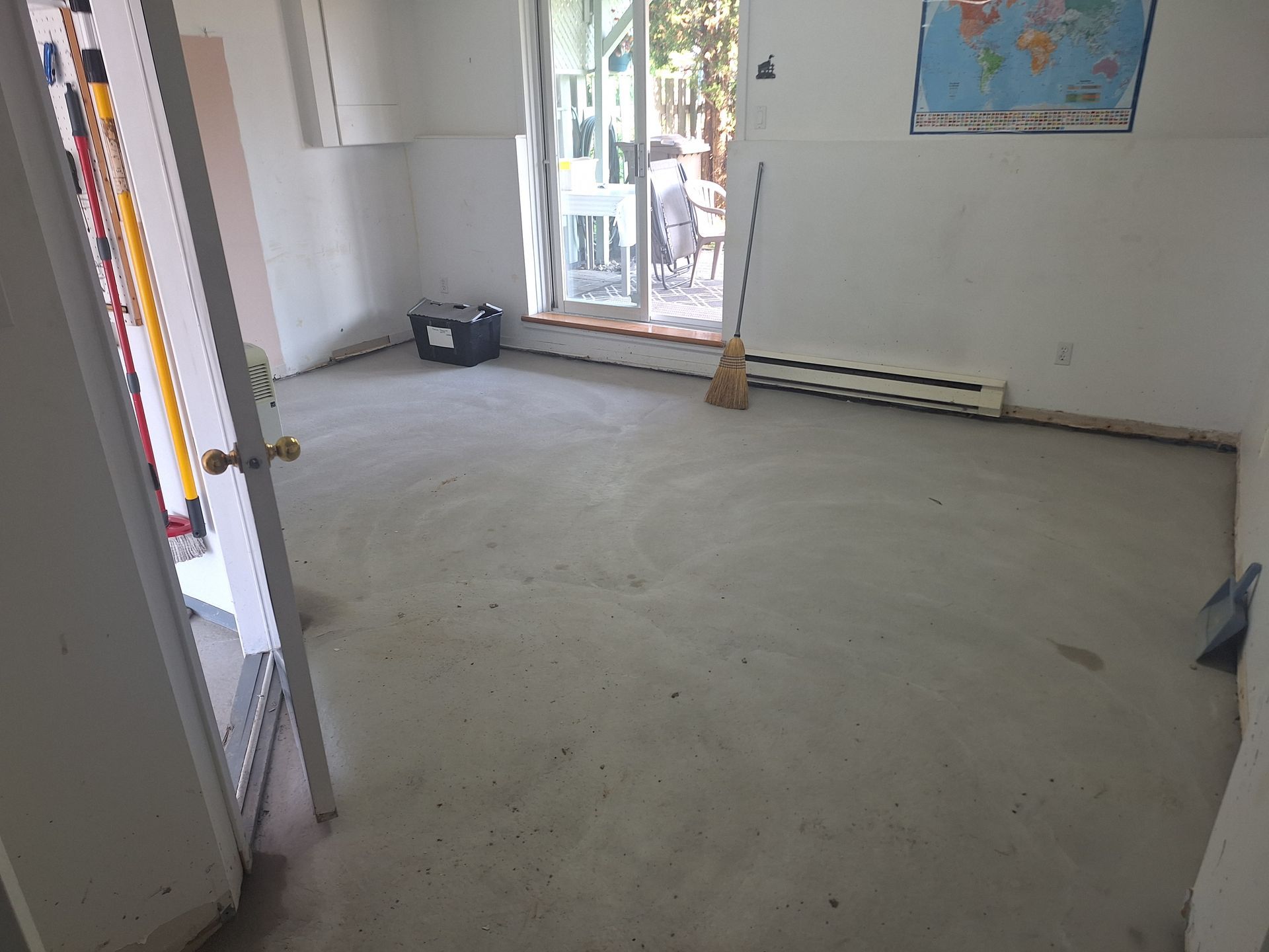 Une pièce vide avec une carte sur le mur et un balai sur le sol.