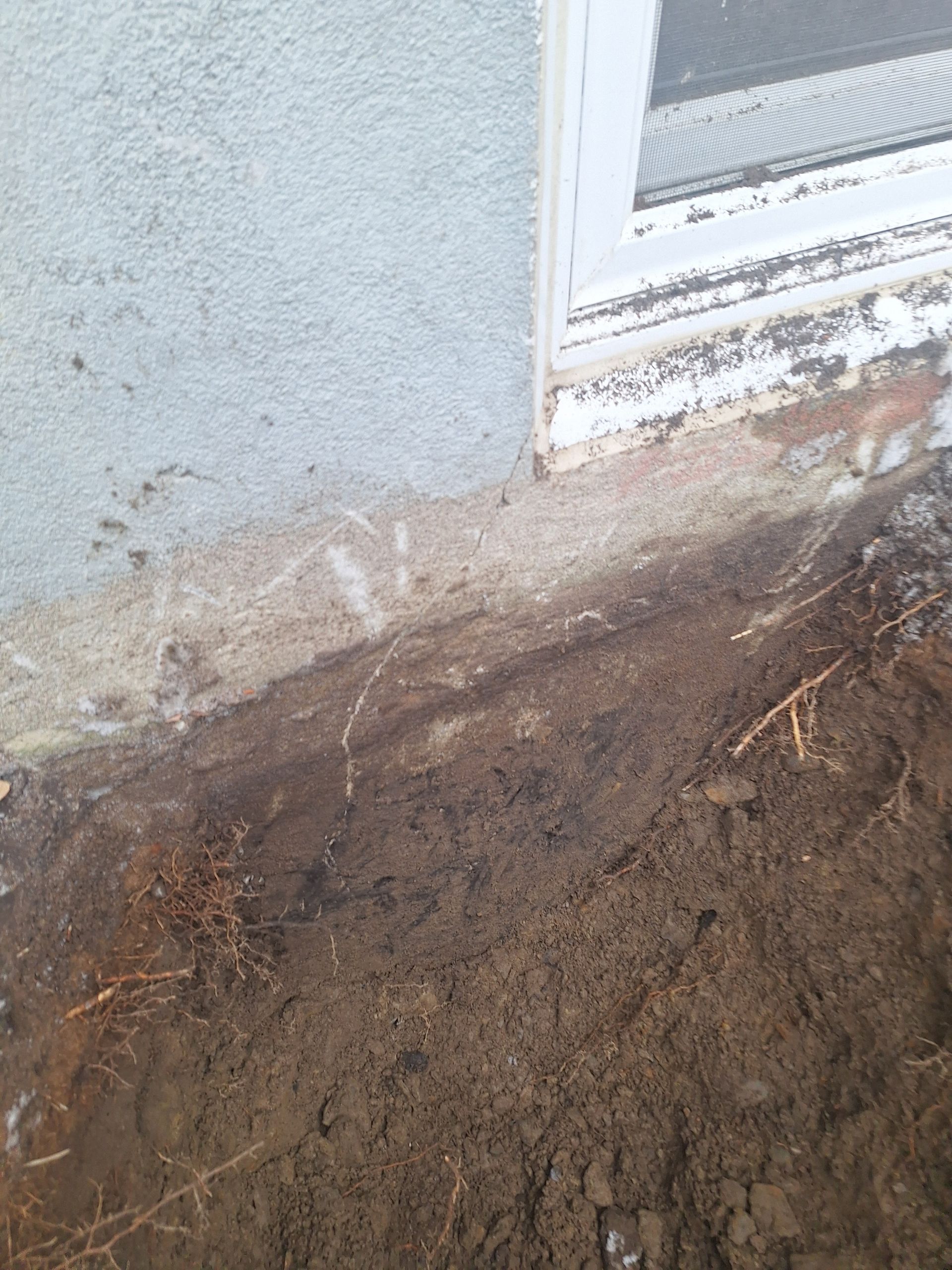 Un tas de terre se trouve à côté d'une fenêtre sur le côté d'un bâtiment.